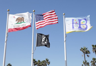 American, California, POW and HB flags flying at HB City Hall